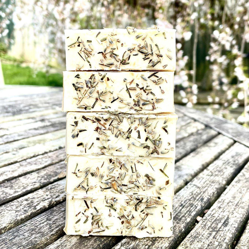 A stack of five natural lavender and patchouli soaps from College Green. They are stacked on an outdoor table