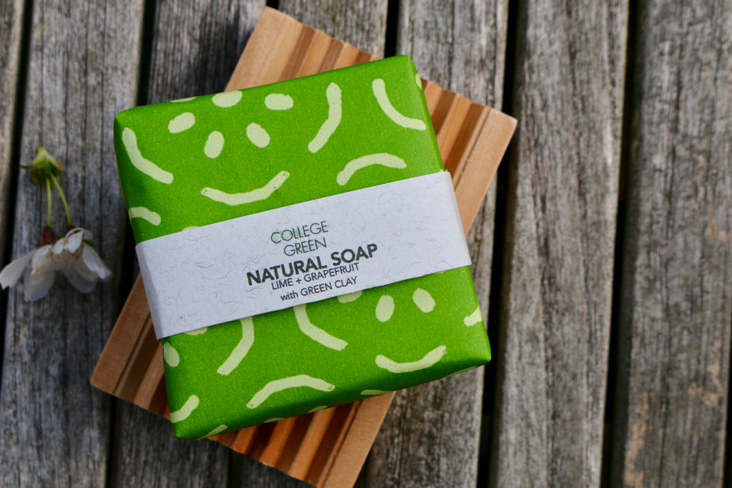 Wrapped bar of Lime and grapefruit soap on a wooden soap dish