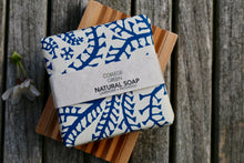 Wrapped bar of Lavender + Patchouli soap sat on a wooden soap dish