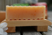 Side view of an unwrapped bar of College Green Lemongrass, Ginger and Oat beer soap next to a wooden soap dish